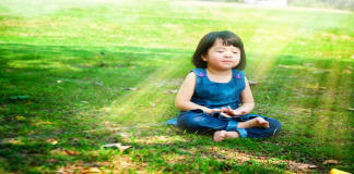 Politiek: maak mindfulness op elke school mogelijk Mindfulness op school: meisje mediteert in het park